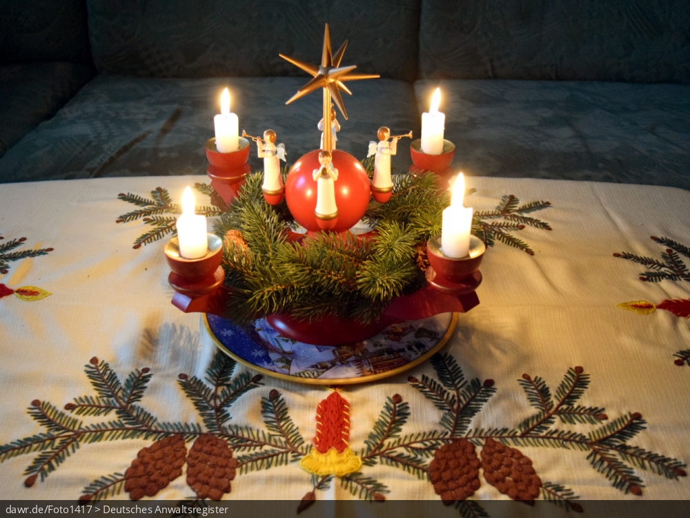 Dieses Foto zeigt einen mit Kerzen beleuchteten Adventskranz, wie er im sächsischen Erzgebirge hergestellt wird. Heutzutage ist solche Volkskunst in ganz Deutschland ein beliebter Weihnachtsschmuck. Dieses Bild eignet sich gut als symbolische Darstellung für alle Themen rund um Weihnachten und speziell zu rechtlichen Fragen bez. der Weihnachtsdekoration.