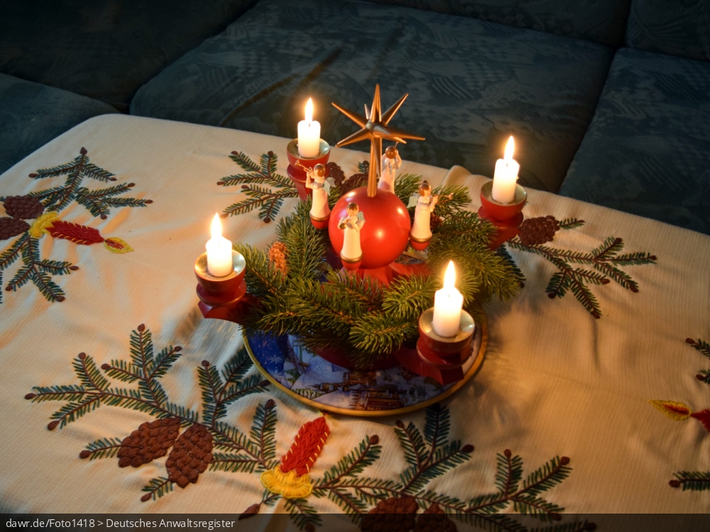 Dieses Foto zeigt einen mit Kerzen beleuchteten Adventskranz, wie er im sächsischen Erzgebirge hergestellt wird. Heutzutage ist solche Volkskunst in ganz Deutschland ein beliebter Weihnachtsschmuck. Dieses Bild eignet sich gut als symbolische Darstellung für alle Themen rund um Weihnachten und speziell zu rechtlichen Fragen bez. der Weihnachtsdekoration.