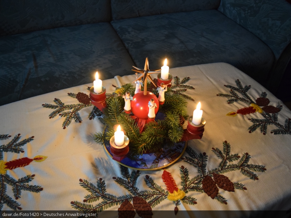 Dieses Foto zeigt einen mit Kerzen beleuchteten Adventskranz, wie er im sächsischen Erzgebirge hergestellt wird. Heutzutage ist solche Volkskunst in ganz Deutschland ein beliebter Weihnachtsschmuck. Dieses Bild eignet sich gut als symbolische Darstellung für alle Themen rund um Weihnachten und speziell zu rechtlichen Fragen bez. der Weihnachtsdekoration.