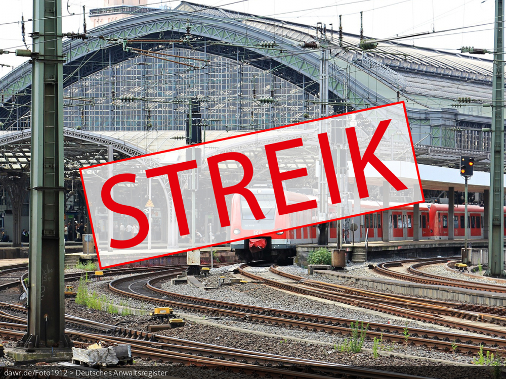 Dieses Bild zeigt eine Gleisanlage, wie sie bei der Bahn in praktisch jeder größeren Stadt zu finden ist. Im Vordergrund sieht ein Schild mit dem Begriff „Streik“. Es handelt sich um eine gut geeignete symbolische Darstellung für das Thema Streik bei der Bahn.