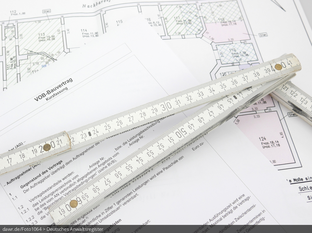 Dieses Foto zeigt einen Bauvertrag, welcher auf einem Bauplan liegt. Auf den Papieren ist ein Zollstock zu sehen, um den Zusammenhang mit der Baubranche offensichtlich zu machen. Auf dem Bauvertrag ist vermerkt, dass er die Allgemeinen Vertragsbedingungen für die Ausführung von Bauleistungen (VOB/B) berücksichtigt. Diese vorformuliertes Klauselwerk ist ein Teil der Vergabe- und Vertragsordnung für Bauleistungen (VOB) (früher: Verdingungsordnung für Bauleistungen) und ist dazu bestimmt in Bauverträgen die Regelungen des hierfür anwendbaren gesetzlichen Werkvertragsrechts zu ergänzen und teilweise zu modifizieren. Hiermit soll das Fehlen von spezifischen Regelungen für das Bauvertragsrecht im deutschen Zivilrecht ausgeglichen werden.