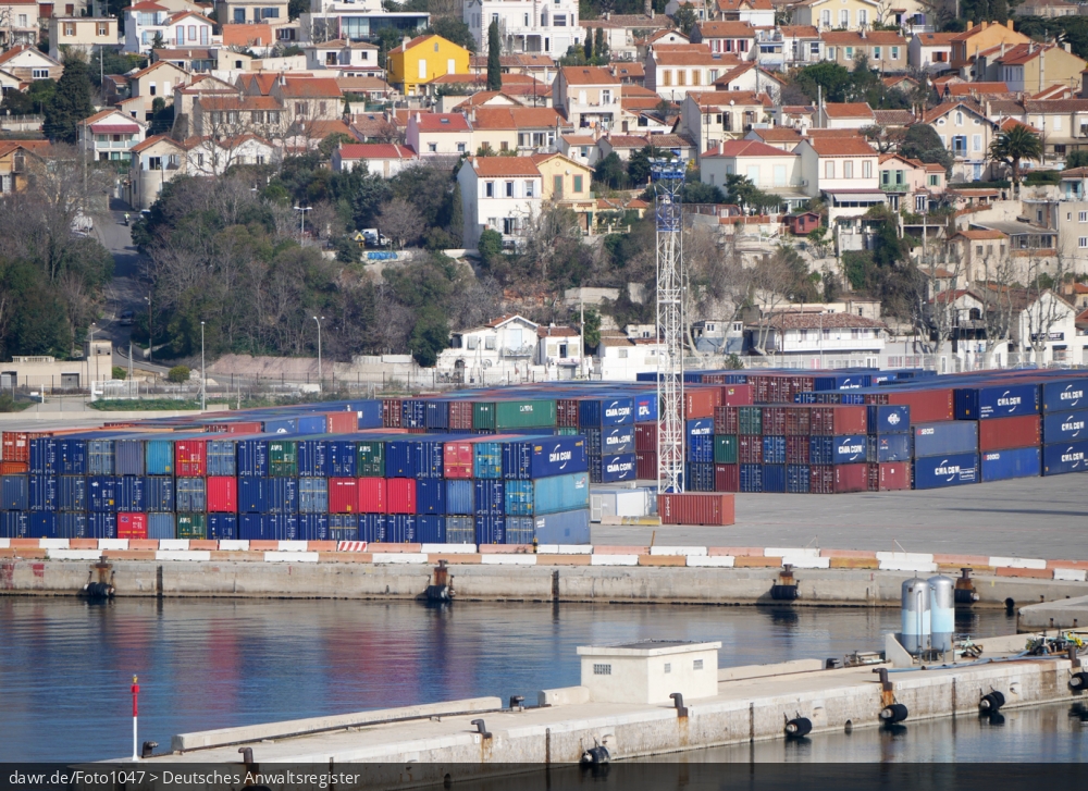 Dieses Foto zeigt einen Liegeplatz für Containerschiffe im Hafen von Marseille (Frankreich). Auf dem Foto ist kein Schiff abgebildet, aber ein Hafenbecken und diverse Stapel von Überseecontainern. Das Bild eigenet sich gut als Symbolfoto für alle Themen rund um den Seehandel.