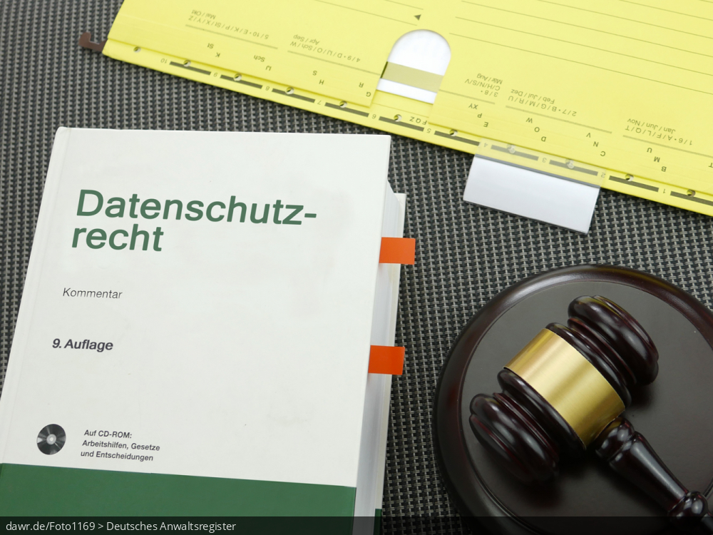 Dieses Foto zeigt einen Schreibtisch, auf dem neben einem gelben Hängehefter (aus einer Aktenregistratur) ein weiß-grünes Fachbuch mit dem Aufdruck „Datenschutzrecht“ liegt. Ergänzt wird diese Zusammenstellung von einem Holzhammer, wie ihn bspw. Richter in den USA verwenden. Dieses Foto eignet sich gut als symbolische Darstellung des Themas Datenschutz und seiner rechtlichen Bedeutung.