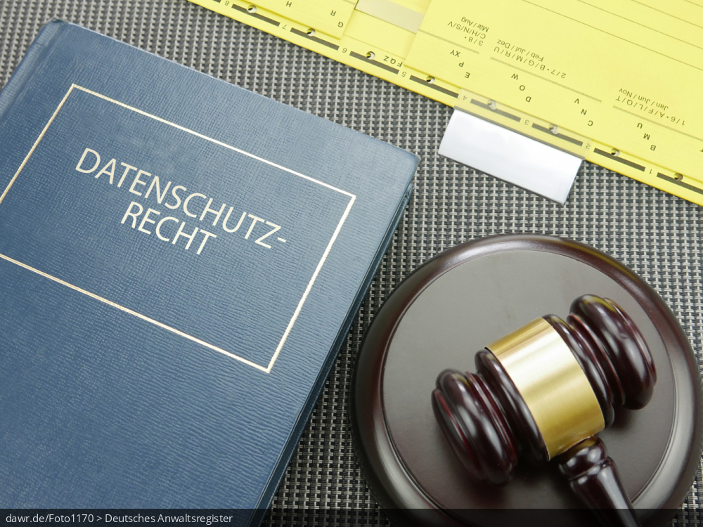 Dieses Foto zeigt einen Schreibtisch, auf dem neben einem gelben Hängehefter (aus einer Aktenregistratur) ein blaues Fachbuch mit dem Aufdruck „Datenschutzrecht“ liegt. Ergänzt wird diese Zusammenstellung von einem Holzhammer, wie ihn bspw. Richter in den USA verwenden. Dieses Foto eignet sich gut als symbolische Darstellung des Themas Datenschutz und seiner rechtlichen Bedeutung.