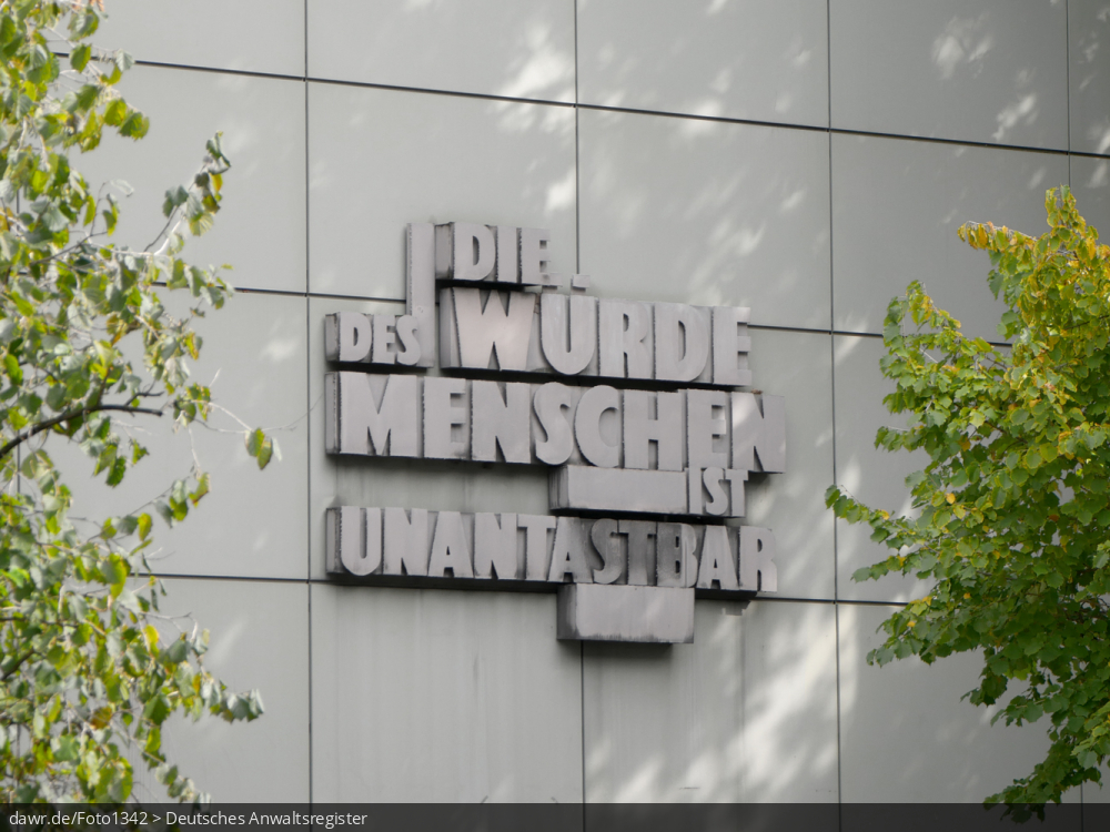 Das Foto zeigt den Schriftzug „Die Würde des Menschen ist unantastbar„ in Anspielung auf Artikel 1 des Grundgesetzes. Angebracht ist dieser Schriftzug am Gebäude des Landgerichts in Frankfurt am Main.