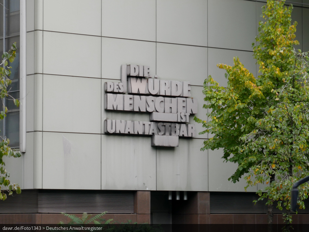 Das Foto zeigt den Schriftzug „Die Würde des Menschen ist unantastbar„ in Anspielung auf Artikel 1 des Grundgesetzes. Angebracht ist dieser Schriftzug am Gebäude des Landgerichts in Frankfurt am Main.