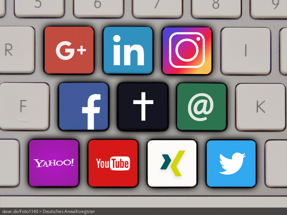 Dieses Foto zeigt eine moderne Tastatur mit verschiedenen speziellen, bunt gefärbten Tasten, welche die Symbole von unterschiedlichen Sozialen Netzwerken und anderen Online-Diensten tragen. In der Mitte dieser Tasten befindet sich eine spezielle, schwarze Taste, die mit einem weißen Kreuz bedruckt ist. Dieses Bild eignet sich gut als symbolische Darstellung für das Thema digitaler Nachlass, also den Umgang mit Online-Daten von Verstorbenen.