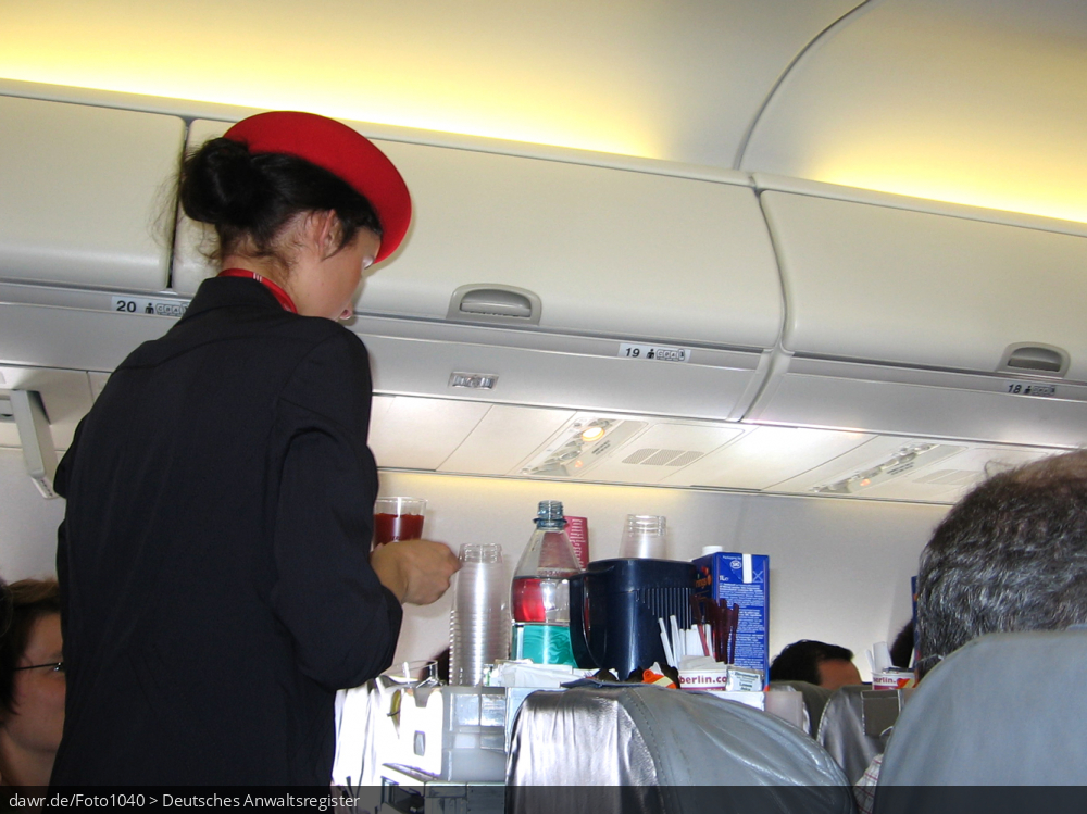 Dieses Foto zeigt eine Flugbegleiterin (Stewardess) beim Getränke ausschenken in einem großen Linienflugezeug