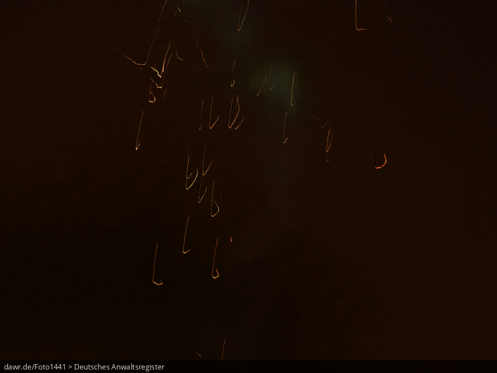 Dieses Foto zeigt einen Funkenregen in der Dunkelheit, wie durch explodierende Silvesterraketen ausgelöst wird. Dieses Bild eignet sich gut als symbolische Darstellung für die Themen Silvester und Feuerwerk.