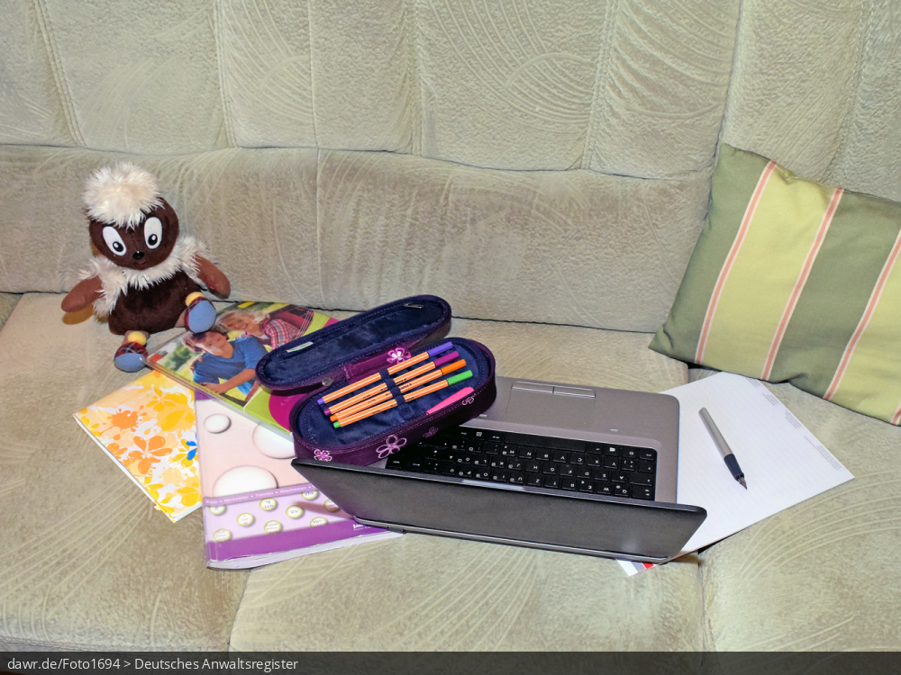 Dieses Foto zeigt ein Sofa auf dem ein Notebook, verschiedene Schulbücher und -hefte, eine Federtasche mit diversen Stiften und ein Füller zu sehen ist. Ergänzt wird die Szenerie durch ein Sofakissen und ein Kuscheltier. Dieses Bild eignet sich gut als symbolische Darstellung für das Thema Home-Scooling oder besser Schule zu Hause, wie es im Zusammenhang mit der Corona-Pandemie deutschlandweit notwendig geworden ist.