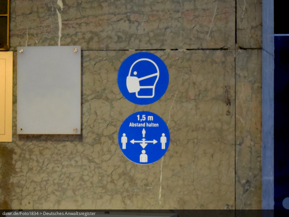 Dieses Foto zeigt zwei Aufkleber an der Hauswand eines Hotels. Der eine Aufkleber fordert zum Einhalten der allgemeinen Maskenpflicht auf. Der Andere fordert einen Abstand zwischen Personen von mindestens 1,5m. Diese symbolische Darstellung eignet sich gut für alle Themen im Zusammenhang mit einer staatlich angeordneten Maskenpflicht bspw. im Rahmen der Corona-Pandemie.