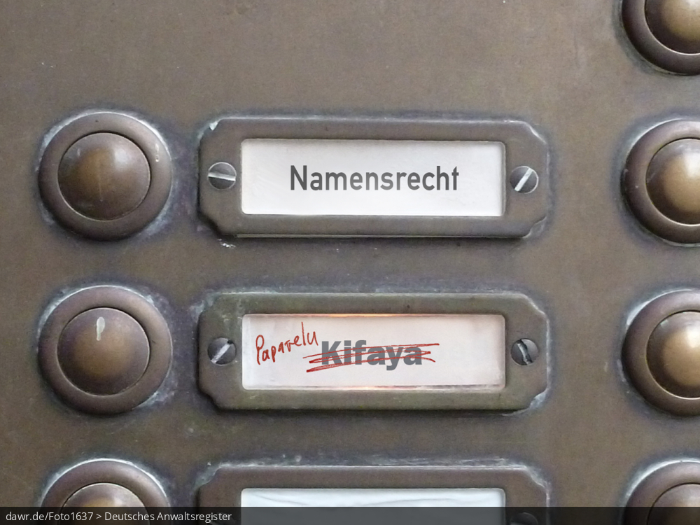 Dieses Foto zeigt einen Teil des Klingelschilds eines Altbau-Mehrfamilienhauses, wobei die Namen „Namensrecht“ und „Kifaya“ zu lesen sind. Der Name „Kifaya“ wurde allerdings durchgestrichen und händisch durch den Namen „Paparelu“ ersetzt, wie man es bspw. nach einer Scheidung machen würde. Diese symbolische Darstellung eignet sich gut für alle Themen rund um das Namensrecht, speziell bez. des Umgangs mit dem Familiennamen bei einer Scheidung.