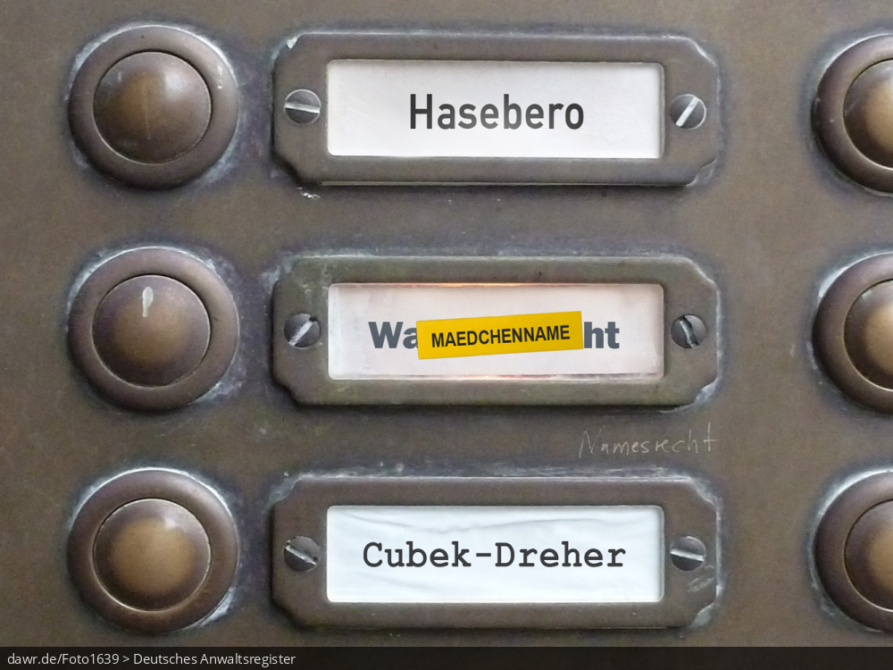 Dieses Foto zeigt einen Teil des Klingelschilds eines Altbau-Mehrfamilienhauses, wobei die Namen „Hasebero“, „Mädchenname“ und „Cubek-Dreher“ zu lesen sind. Mit dem Namen „Mädchenname“ wurde ein anderer Name überklebt, wie man es bspw. nach einer Scheidung oder einem Umzug machen würde. Auf die Klingeltafel selbst wurde der Schriftzug „Namensrecht“ gekritzelt. Diese symbolische Darstellung eignet sich gut für alle Themen rund um das Namensrecht, speziell bez. des Umgangs mit dem Mädchennamen einer Frau bei der Scheidung.