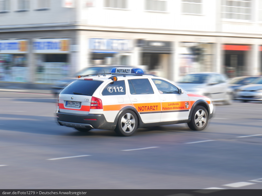 Dieses Foto zeigt einen Notarztwagen, wie er schnell über eine Kreuzung fährt. Dieses Bild eignet sich gut als symbolische Darstellung für alle Themen rund um die ärztliche Vorsorgung im Notfall oder die Einsätze der Feuerwehr.
