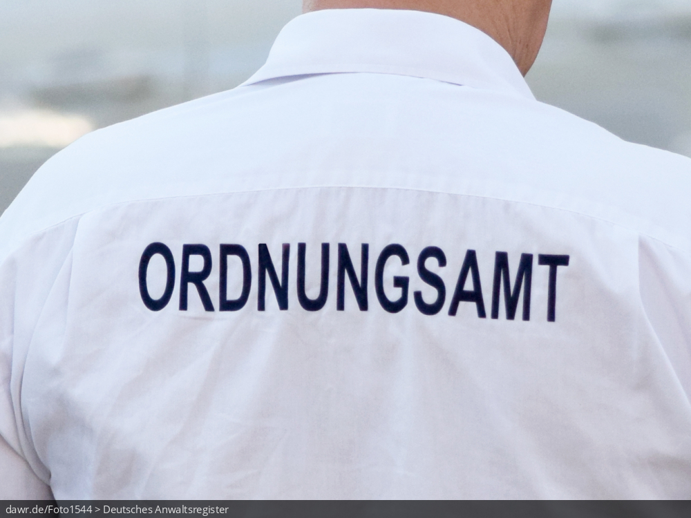 Dieses Foto zeigt einen Mitarbeiter des Ordnungsamtes. Auf seinem weißen Hemd sieht man den Schriftzug „Ordnungsamt“. Das Ordnungsamt ist eine Organisationseinheit innerhalb der Kommunalverwaltung in Deutschland, welche üblicherweise für die Abwehr von Gefahren und die öffentliche Sicherheit oder Ordnung zuständig ist.