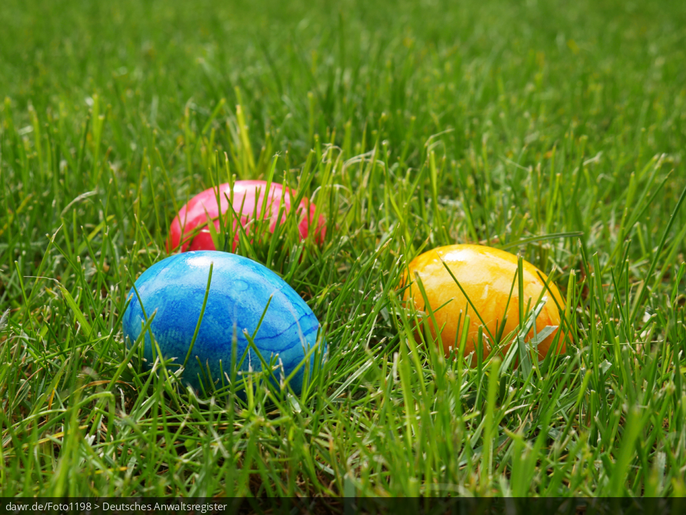 Dieses Foto zeigt drei bunte Ostereier, die im Gras liegen. Eine solches Bild eignet sich gut als symbolische Darstellung für das Osterfest.