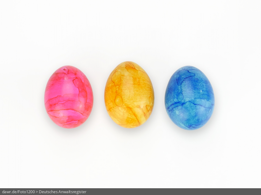 Dieses Foto zeigt drei bunte Ostereier, die auf einer weißen Fläche liegen. Eine solches Bild eignet sich gut als symbolische Darstellung für das Osterfest.