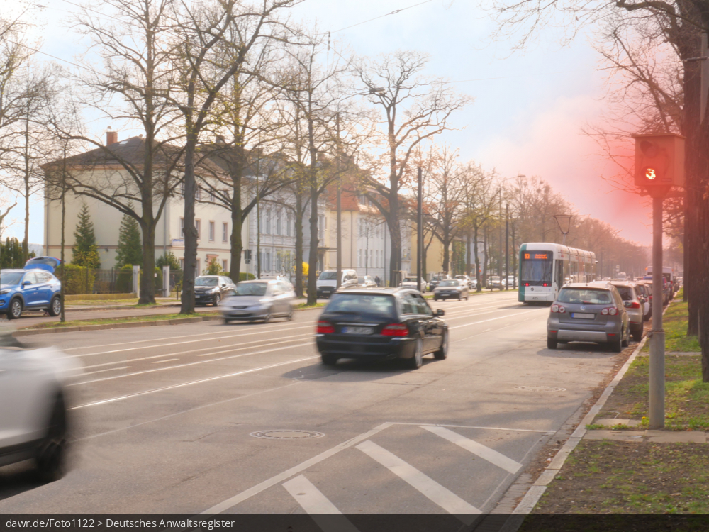 Dieses Foto zeigt eine Straße, an der eine Geschwindigkeitsüberwachungsanlage vom Typ TRAFFIPAX TraffiPho aufgestellt wurde, welche gerade ein Auto blitzt. Auch wenn hier ein spezieller Typ von Geschwindigkeitsüberwachungsanlage dargestellt wird, ist es möglich dieses Bild als symbolische Darstellung für Themen in Zusammenhang mit Geschwindigkeitsverstößen und ihren Konsequenzen zu verwenden.