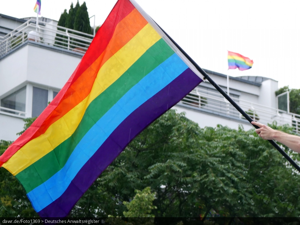 Das Foto zeigt eine Regenbogenfahne, die während einer Demonstration geschwenkt wurde. Als internationales Symbol der Lesben- und Schwulenbewegung kann dieses Bild mit der Regenbogenfahne als symbolische Darstellung für Themen wie Gleichberechtigung oder Ehe für alle gut geeignet sein.