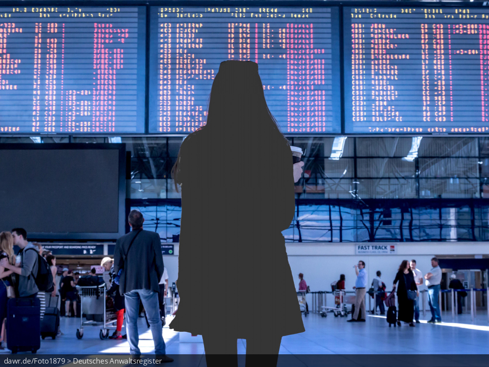 Dieses Foto zeigt den Terminal eines Flughafens und eine Frau, welche vor einer großen Fluganzeige steht. Die Frau ist allerdings nur als Silhouette dargestellt, ganz so als wäre sie ausradiert worden. Diese Darstellung eignet sich wegen dem Ausradieren gut für das Thema Reiserücktritt.
