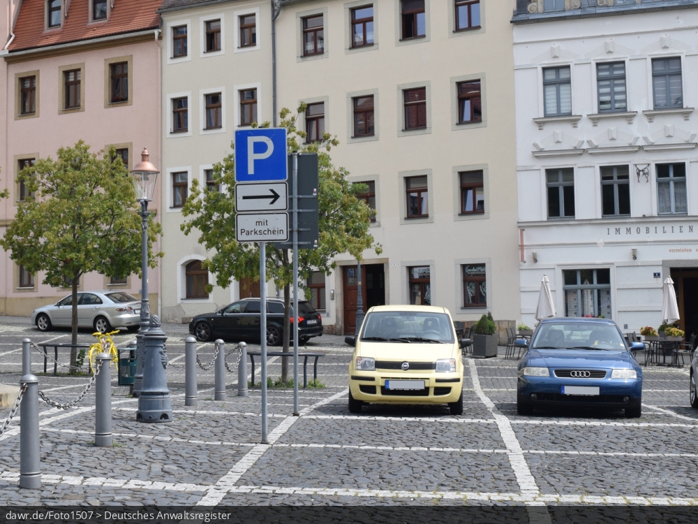 Das Foto zeigt ein Schild, welches darauf hinweist, dass man auf diesem Parkplatz einen Parkschein benötigt und in welcher Richtung der Parkautomat zu finden ist. Dieses Bild eignet sich gut als symbolische Darstellung für das Thema Parkraumbewirtschaftung oder allgemeiner Parken in der Stadt.