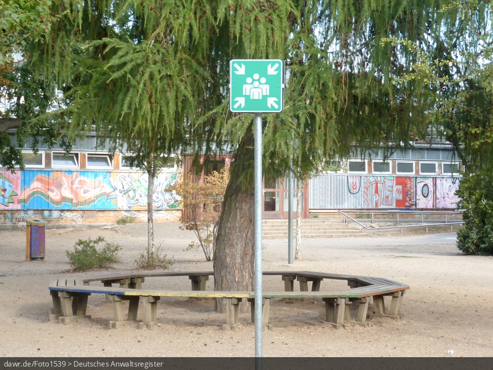 Dieses Foto zeigt ein Schild auf einem Schulhof, mit dem Sammelstellen in bzw. vor öffentlichen Gebäuden markiert werden. Sammelstellen werden festgelegt, um in einem Notfall die geordnete Evakuierung des Gebäudes über die Notausgänge sicher zu stellen. Diese Bild ist eine passende Illustration für alle Fragen im Zusammenhang mit Notfallplänen zur Evakurierung von Gebäuden.