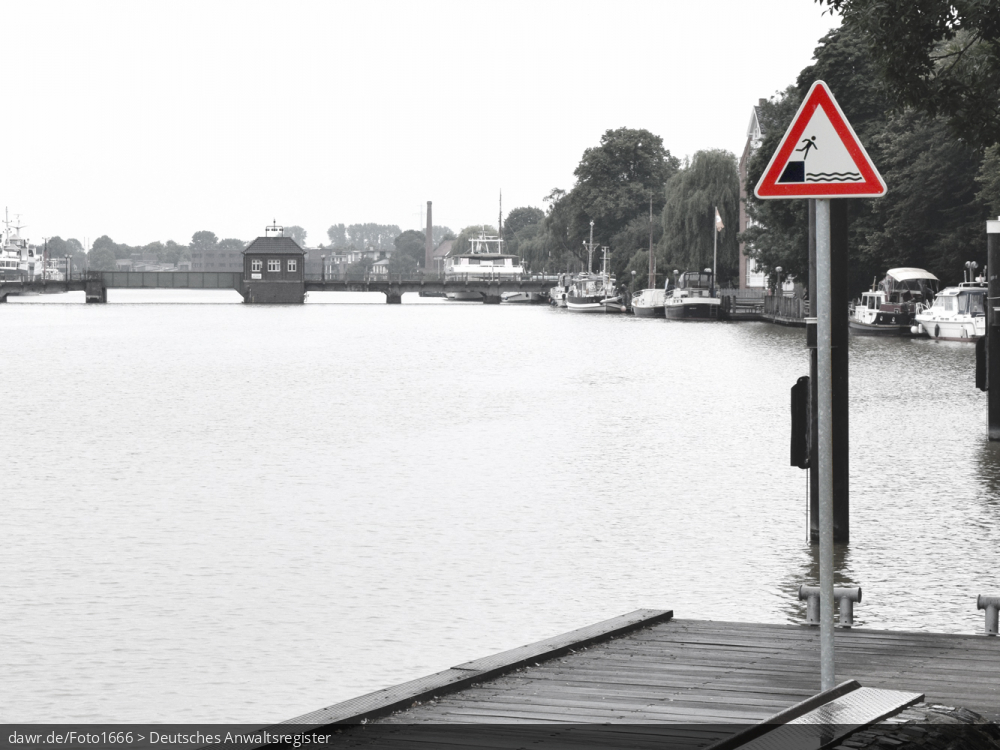 Dieses Foto zeigt einen Steg am Ufer eines Flusses, welche passend mit einem Warnschild „Achtung Absturzgefahr“ ergänzt wurde. Mit diesem Bild liegt Ihnen eine sehr passende Illustration für alle rechtlichen Fragen bez. des Warnschildes „Achtung Absturzgefahr“ vor.