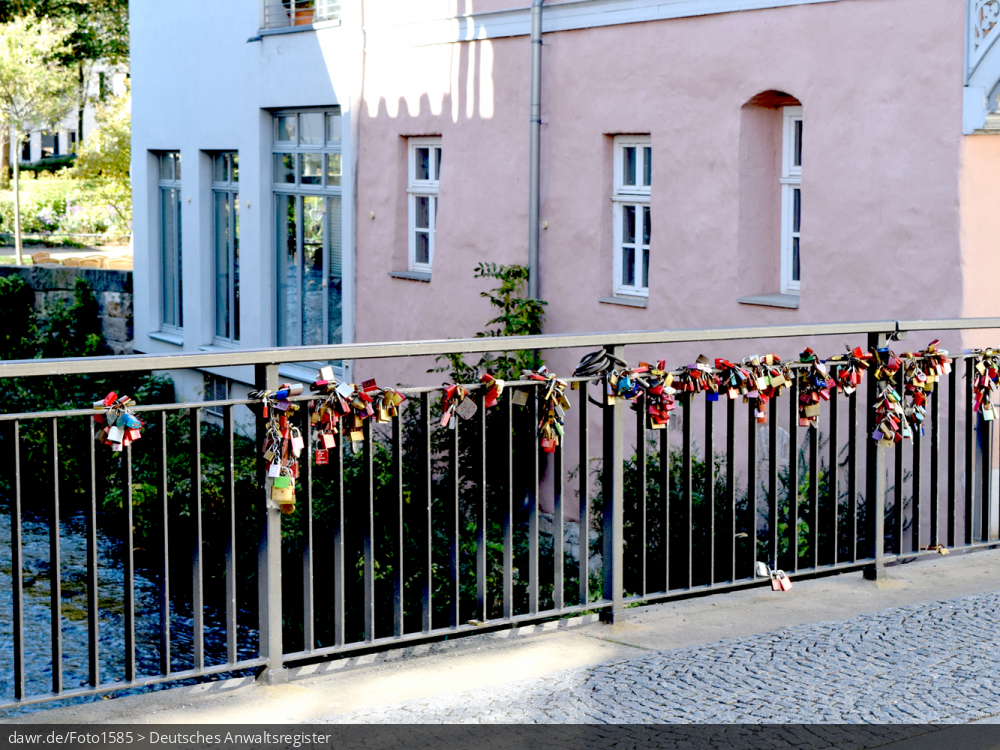 Dieses Foto zeigt das Geländer einer Brücke an dem viele Vorhängeschlösser angebracht wurden. Dies geht auf einen romantischen Brauch aus Italien zurück, nach dem Liebespaare, welche gemeinsam ein Vorhängeschloß an ein Brückengeländer anbringen und anschließend den dazugehörigen Schlüssel in den Fluß werfen, viel Glück in ihrer Beziehung haben werden. Dieses Bild eignet sich gut als symbolische Darstellung im Zusammenhang mit den rechtlichen Fragen, die solche Bräuche aufwerfen.