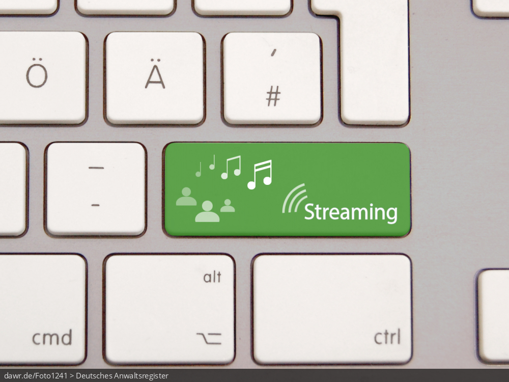 Dieses Foto zeigt eine moderne Tastatur mit einer speziellen, grünen Taste. Auf dieser Taste sind stilisierte Personen und der Schriftzug „Streaming“ aufgedruckt. Den Personen fliegen Noten zu. Diese Grafik eignet sich gut als symbolische Darstellung für alle Themen rund um das Streamen von Musik.