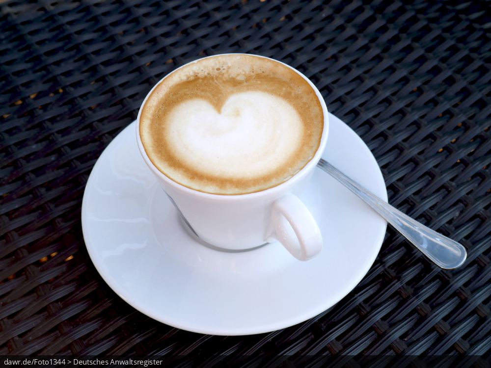 Dieses Foto zeigt eine Tasse Cappuchino mit dem typischen Häubchen aus Milchschaum, in dem sich ein Muster abbildet.