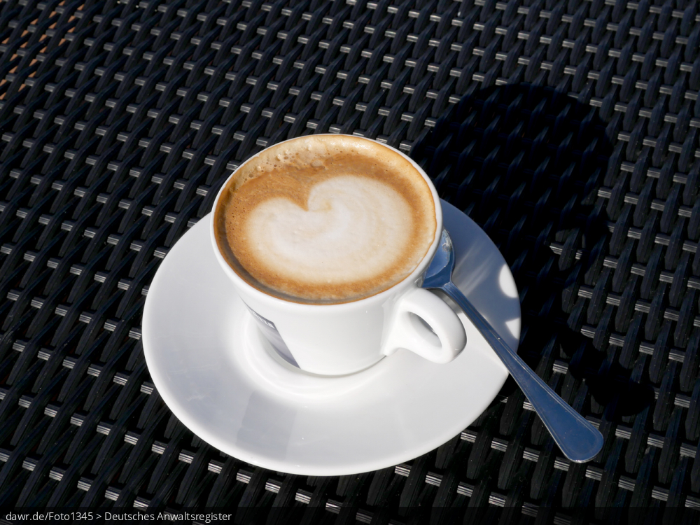 Dieses Foto zeigt eine Tasse Cappuchino mit dem typischen Häubchen aus Milchschaum, in dem sich ein Muster abbildet.