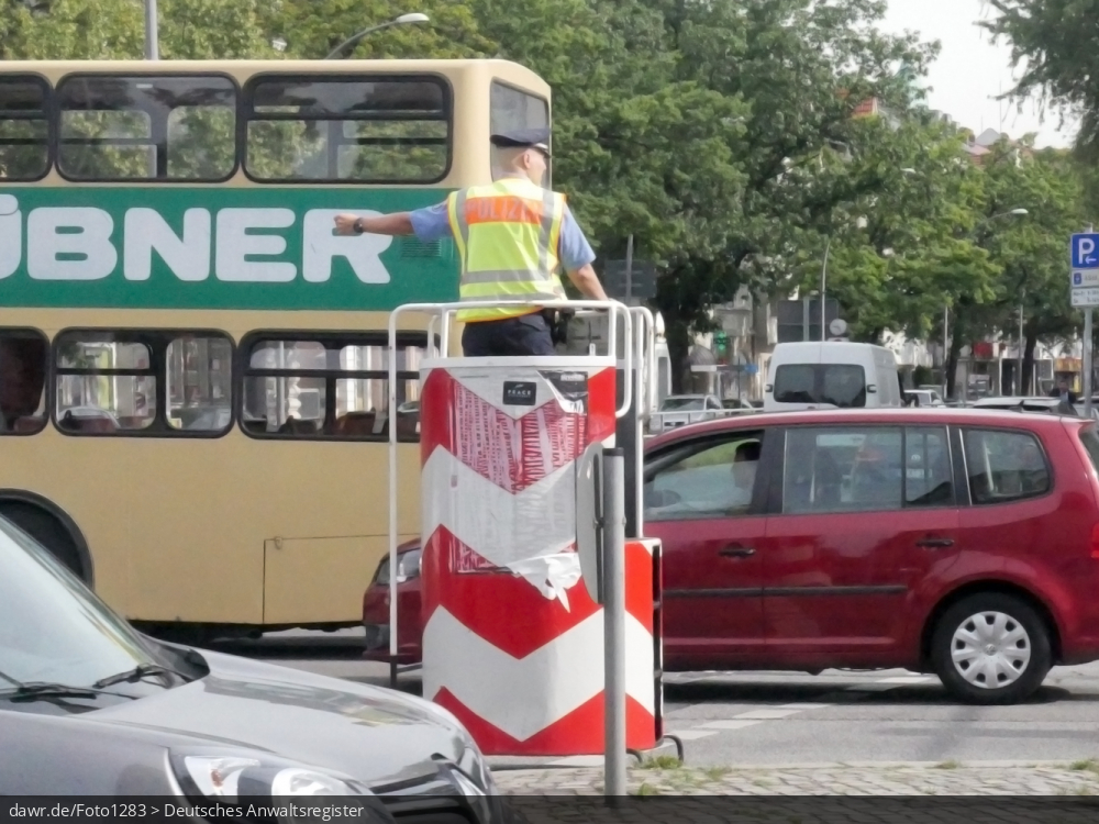 Dieses Foto zeigt einen Verkehrspolizisten, welche den Verkehr auf einer großen Straßenkreuzung regelt, womit es sich gut für das Thema Verkehr im Städten eignet.