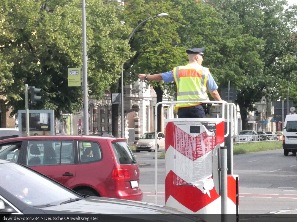 Dieses Foto zeigt einen Verkehrspolizisten, welche den Verkehr auf einer großen Straßenkreuzung regelt, womit es sich gut für das Thema Verkehr im Städten eignet.