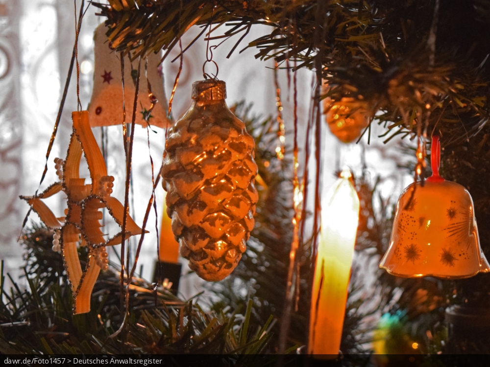 Dieses Foto zeigt eine Weihnachtskugel in Form eines Zapfens und eine kleine Porzellan-Glocke, wie sie an einem Weihnachtsbaum hängen. Diese Abbildung eignet sich gut als symbolische Darstellung für die Themen Weihnachten und Weihnachtsschmuck.