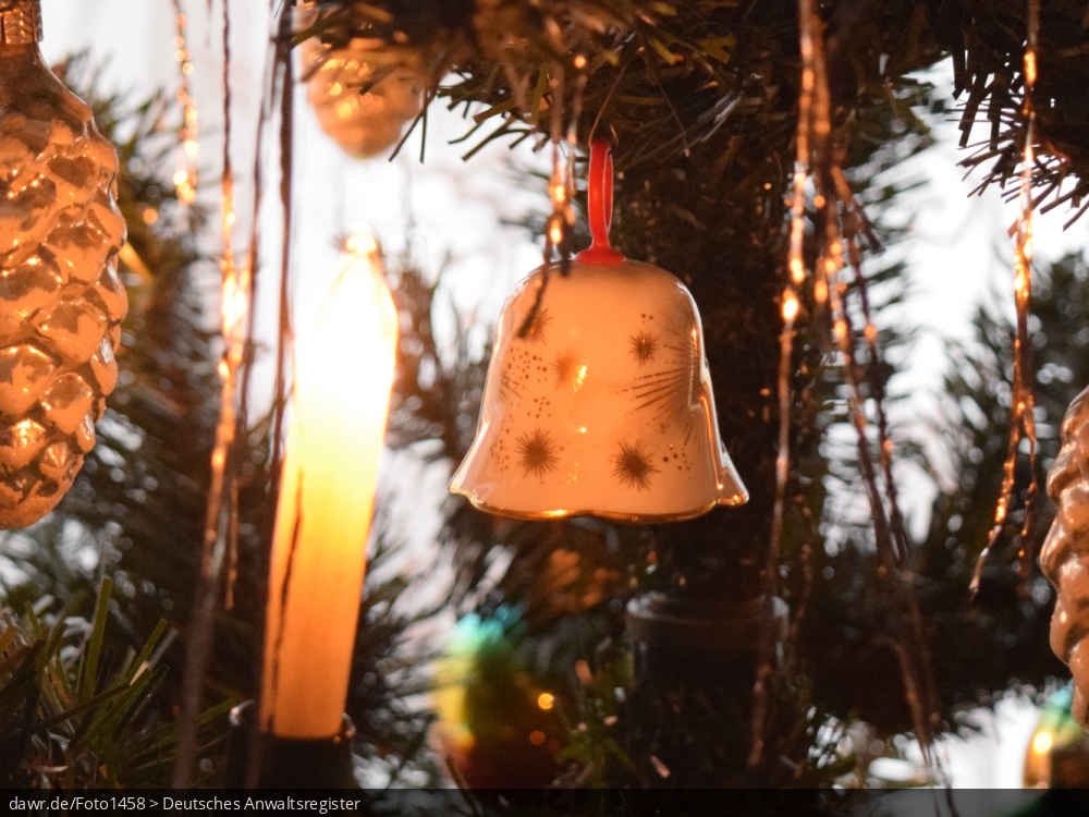Dieses Foto zeigt eine kleine Porzellan-Glocke, wie sie an einem Weihnachtsbaum hängt. Diese Abbildung eignet sich gut als symbolische Darstellung für die Themen Weihnachten und Weihnachtsschmuck.
