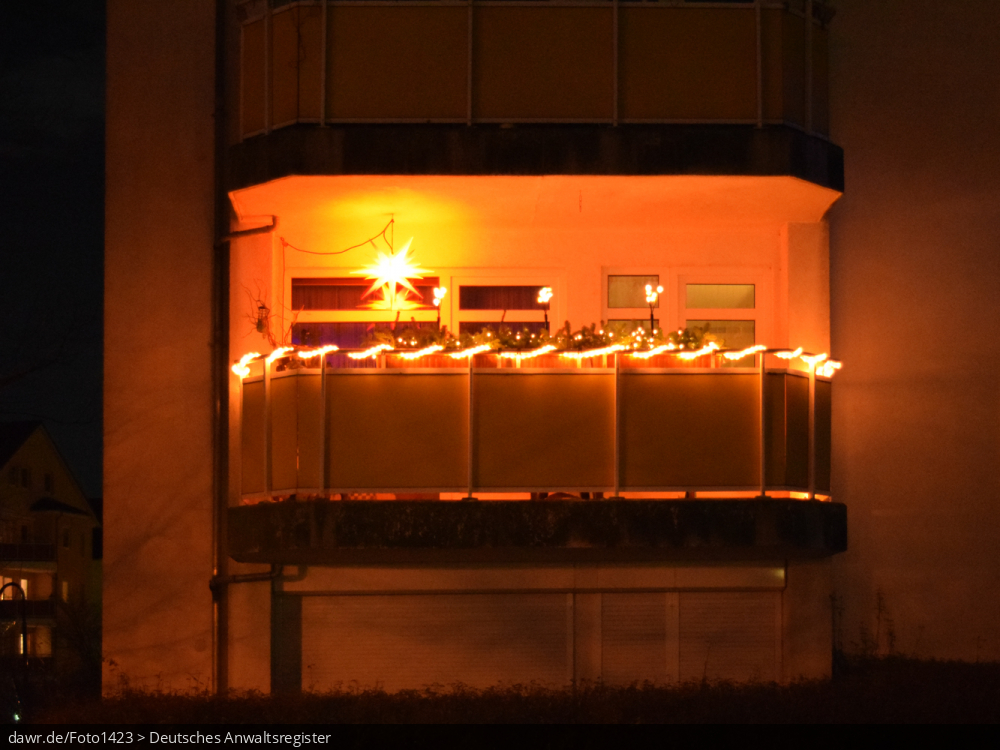 Dieses Foto zeigt einen Balkon, der zu Weihnachten mit Lichterketten geschmückt wurde und die Dunkelheit erhellt. Dieses Bild eignet sich gut als symbolische Darstellung für alle Themen rund um Weihnachten und speziell zu rechtlichen Fragen bez. der Weihnachtsdekoration.