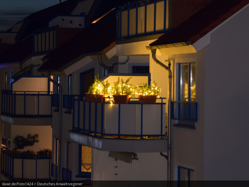 Dieses Foto zeigt einen Balkon, der zu Weihnachten mit Lichterketten geschmückt wurde und die Dunkelheit erhellt. Dieses Bild eignet sich gut als symbolische Darstellung für alle Themen rund um Weihnachten und speziell zu rechtlichen Fragen bez. der Weihnachtsdekoration.
