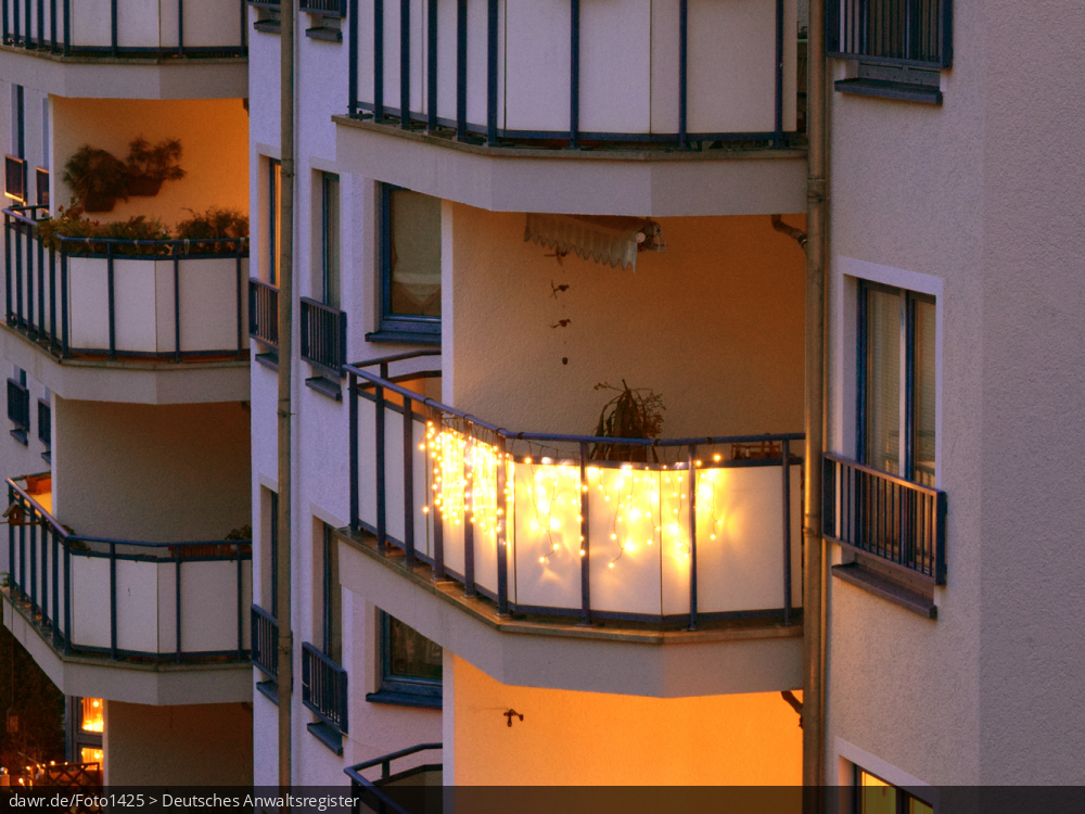 Dieses Foto zeigt einen Balkon, der zu Weihnachten mit Lichterketten geschmückt wurde und die Dunkelheit erhellt. Dieses Bild eignet sich gut als symbolische Darstellung für alle Themen rund um Weihnachten und speziell zu rechtlichen Fragen bez. der Weihnachtsdekoration.