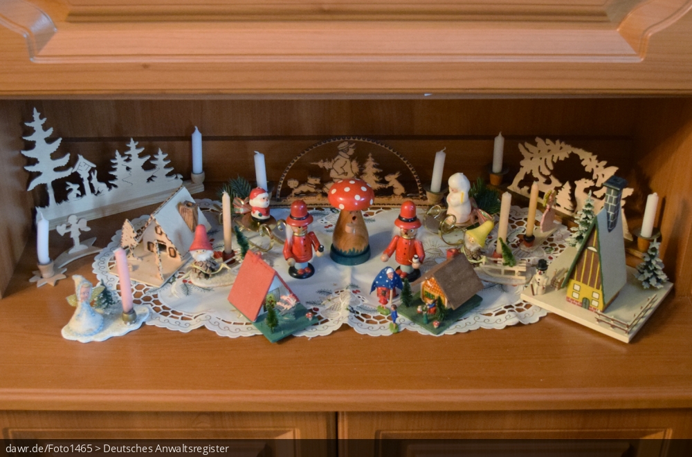 Dieses Foto zeigt erzgebirgischen Weihnachtsschmuck im einem Fach einer Schrankwand. Neben kleinen Schwippbögen, finden sich Rauchermänner, Räucherhäuschen, und verschiedene Kerzhalter. Diese Abbildung eignet sich gut als symbolische Darstellung für die Themen Weihnachten und Weihnachtsschmuck.