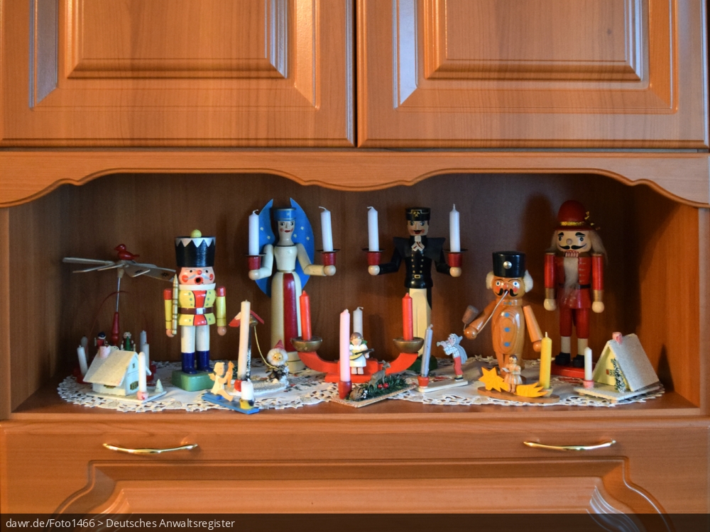 Dieses Foto zeigt erzgebirgischen Weihnachtsschmuck im einem Fach einer Schrankwand. Neben Nussknackern, finden sich Engel und Bergmann, sowie verschiedene Kerzenhalter und Räucherhäuschen. Diese Abbildung eignet sich gut als symbolische Darstellung für die Themen Weihnachten und Weihnachtsschmuck.