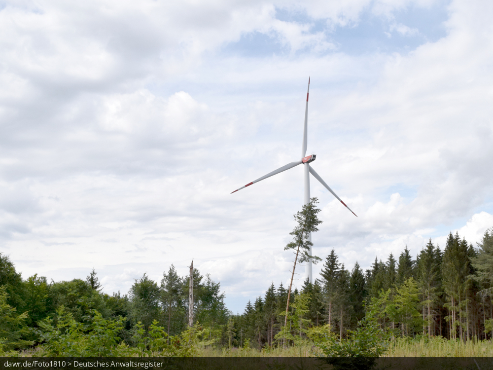 Dieses Bild zeigt eine Windkraftanlage in einem Waldgebiet. Es ergibt sich so ein passendes Bild für Themen rund um erneuerbare Energien, Windkraft oder allgemein der umweltfreundlichen Stromerzeugung.