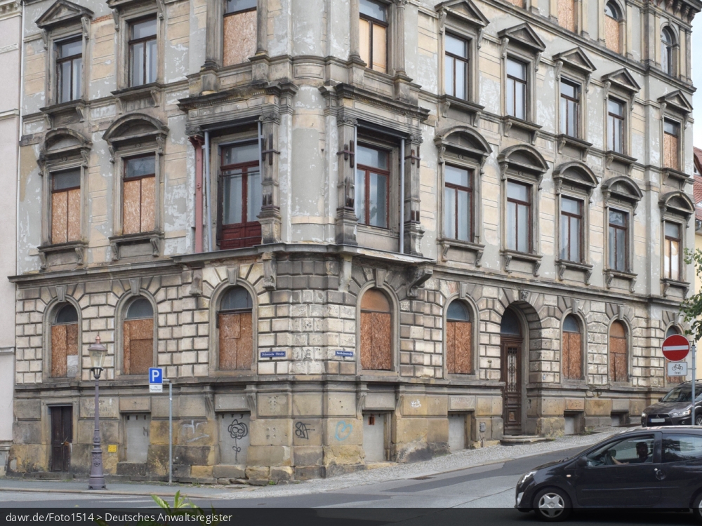 Dieses Foto zeigt eine baufälliges Wohnhaus mit vernagelten Fenstern und Türen, wie es in vielen (Klein)Städten zu finden ist. Die Gründe für einen solch schlechten Erhaltungszustand sind oft ungeklärte Eigentumsverhältnisse, ausbleibende staatliche Mittel oder einfach fehlende Investoren. Mit seinem schlechten Erhaltungszustand, kann dieses Gebäude symbolisch für Themen wie Wohnungsbau, Mietmängel oder auch Schrottimmobilien stehen.
