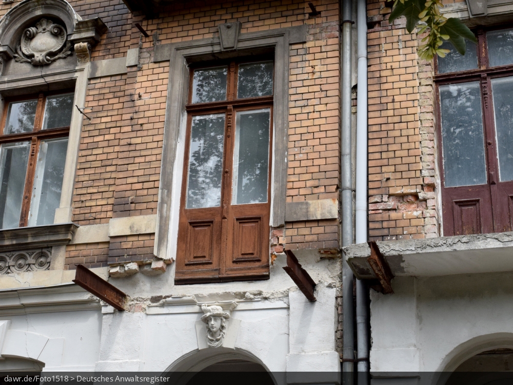 Dieses Foto zeigt eine baufälliges Wohnhaus mit bröckelndem Putz und abgebrochenen Balkonen, wie es in vielen (Klein)Städten zu finden ist. Die Gründe für einen solch schlechten Erhaltungszustand sind oft ungeklärte Eigentumsverhältnisse, ausbleibende staatliche Mittel oder einfach fehlende Investoren. Mit seinem schlechten Erhaltungszustand, kann dieses Gebäude symbolisch für Themen wie Wohnungsbau, Mietmängel oder auch Schrottimmobilien stehen.