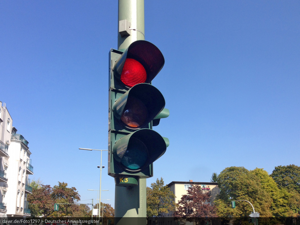 Das Foto zeigt eine rot zeigende Ampel, wie sie auf vielen Kreuzungen zu finden ist und zur Regelung des Autoverkehrs dient.