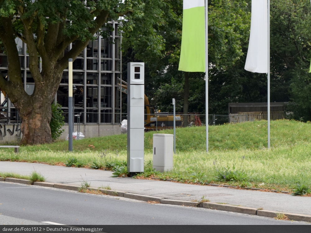 Dieses Foto zeigt eine stationäre Säule zur Geschwindigkeitskontrolle an einer Hauptstraße. Das Bild kann gut als symbolische Darstellung für Themen in Zusammenhang mit Geschwindigkeitsverstößen und ihren Konsequenzen verwendet werden.