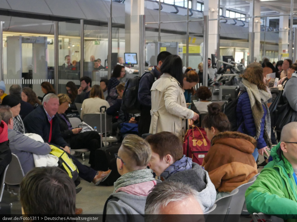 Das Foto zeigt wartende Passagiere auf einem Flughafen. Dieses Bild eignet sich gut als symbolische Darstellung für Themen rundum den Flugverkehr und Flugreisen, einschließlich Flugverspätungen.